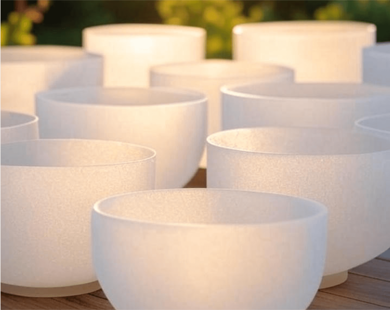 A row of frosted white crystal singing bowls in warm light